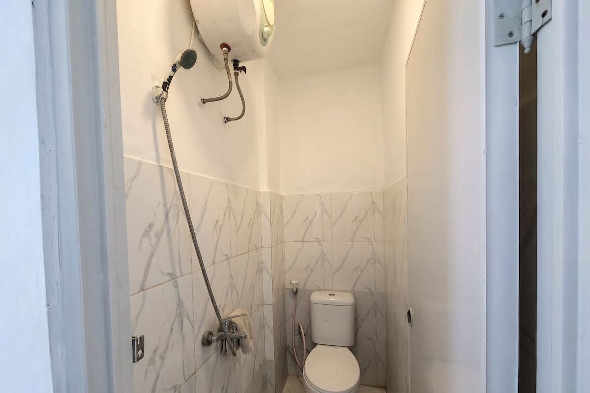 A small bathroom with a toilet, a shower, and a towel rack.