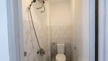 A small bathroom with a toilet, a shower, and a towel rack.