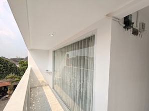 Un balcón moderno con puerta de cristal, una mesita y una silla.