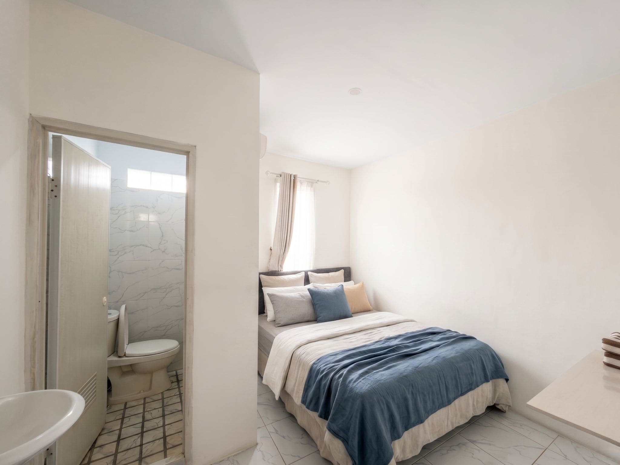 A bedroom with a bed, a bathroom with a toilet, and a shower area.