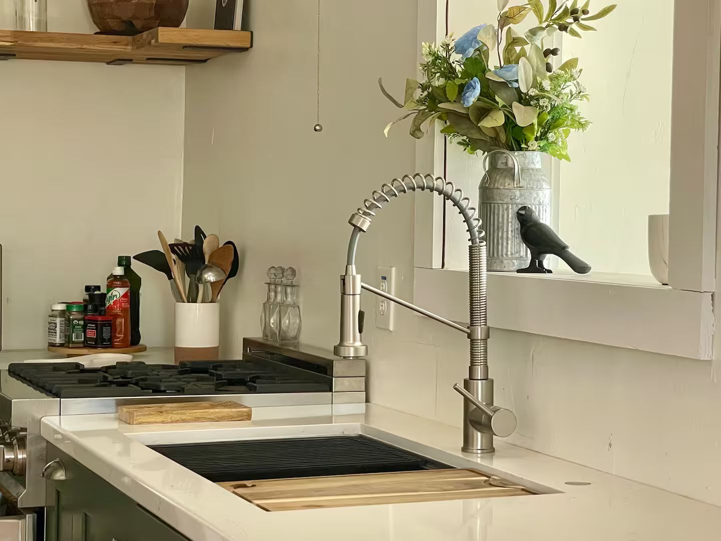 A kitchen with a stainless steel range, a modern faucet, and a window sill with a vase of flowers.