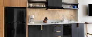 Eine moderne Küche mit einem schwarzen Kühlschrank, einer Kaffeemaschine, einem Mixer und einem Messerblock.