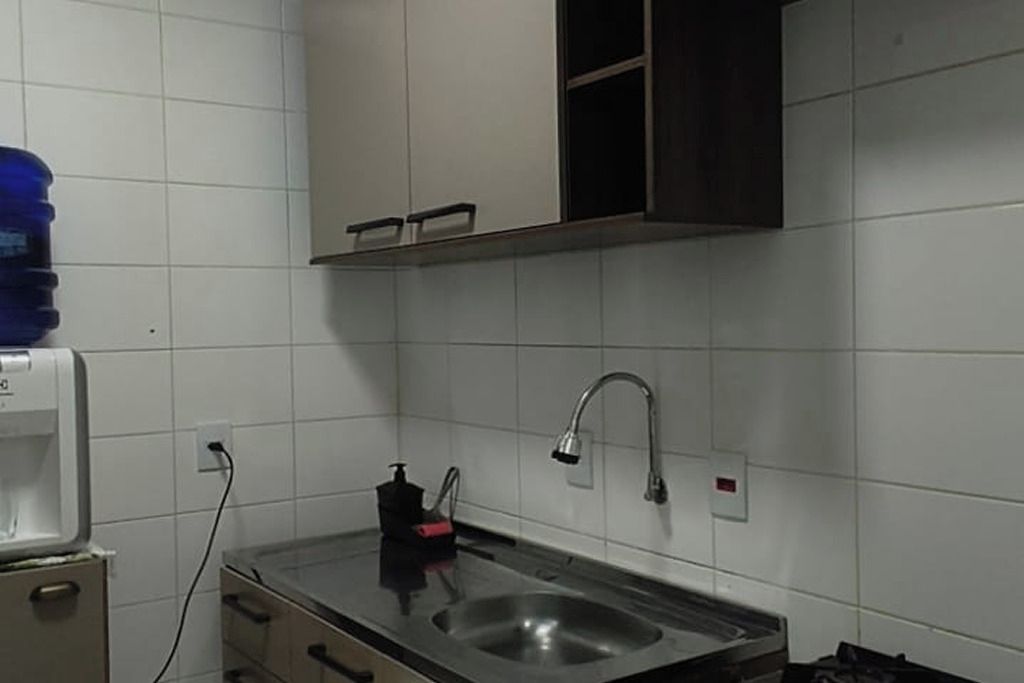 Una cocina con un lavamanos de acero inoxidable, un grifo y un dispensador de agua.