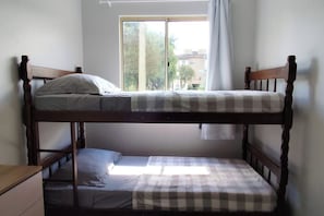 Een stapelbed met raam, gordijnen en uitzicht op gebouwen.