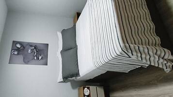 A bedroom with a bed, a nightstand, and a wall-mounted artwork.