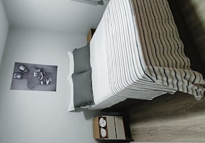 A bedroom with a bed, a nightstand, and a wall-mounted artwork. - Entire apartment in São José dos Pinhais (São José dos Pinhais)