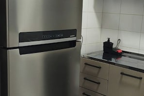 A stainless steel refrigerator with a digital control panel, a black countertop, and a red soap dispenser. - Entire apartment in São José dos Pinhais (São José dos Pinhais)