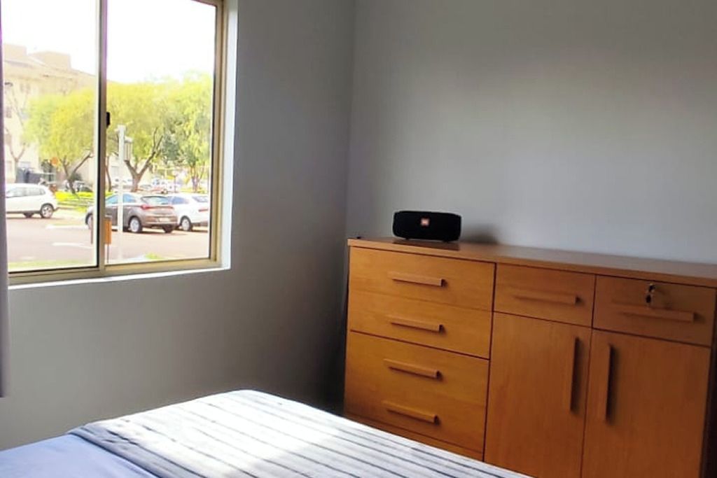 Una habitación con una cama, una ventana y un aparador de madera.
