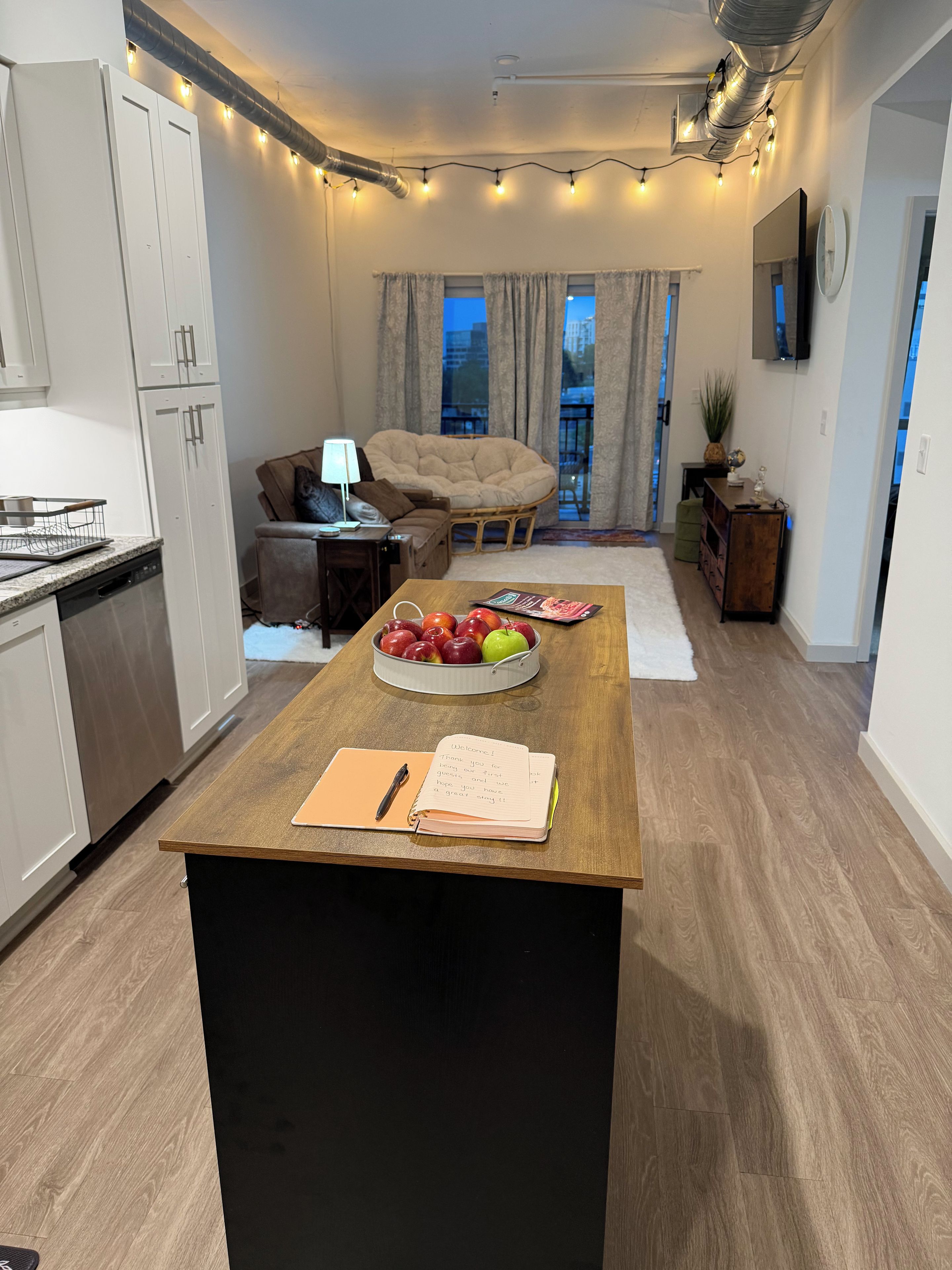 Une cuisine moderne dotée d’un îlot central, d’un coin repas avec un canapé et offrant une vue sur la ville grâce à de grandes fenêtres.