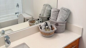 A bathroom with a sink, mirror, and a towel rack with towels. - Bright + Spacious Basement Suite by the Beach (VANCOUVER)
