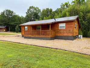 Une cabane en bois avec une véranda, un toit en métal et une allée gravillonnée.
