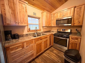 A kitchen with wooden cabinets, a stainless steel stove, a microwave, and a coffee maker.
