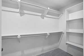 A walk-in closet with open shelving and a metal rod for hanging items. - Stone and Sage - 3BR/2BA - Quiet Family Retreat (Lubbock)