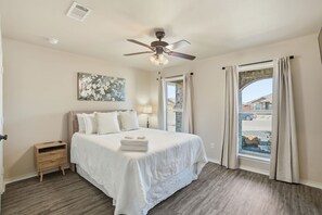 A bedroom with a bed, a nightstand, a ceiling fan, and a window with curtains. - Stone and Sage - 3BR/2BA - Quiet Family Retreat (Lubbock)
