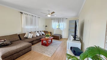 A living room with a sectional sofa, a coffee table, a television, and a ceiling fan.