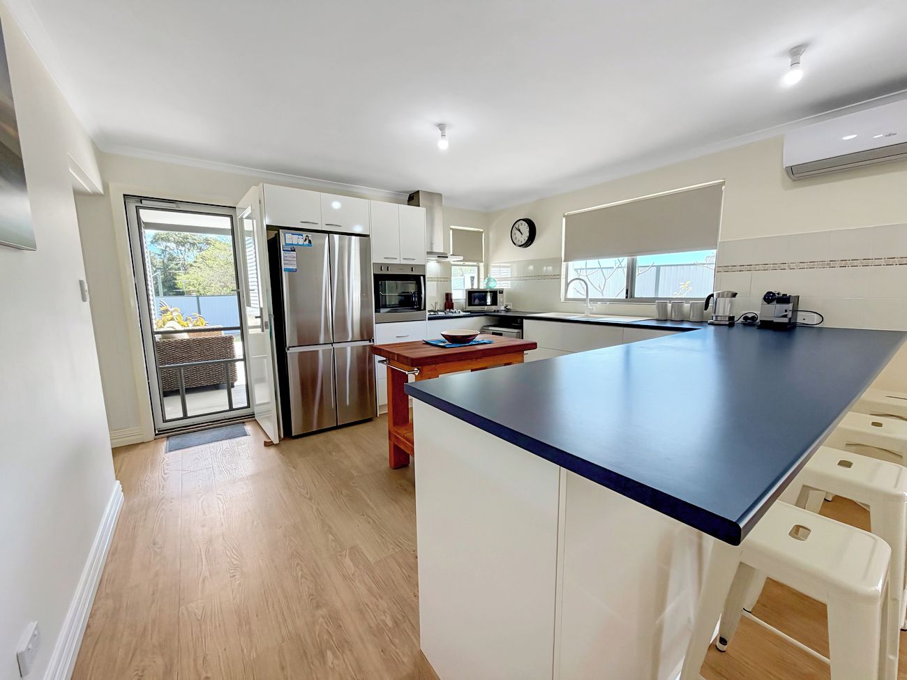 A modern kitchen with a central island, stainless steel appliances, and a view to the outside.
