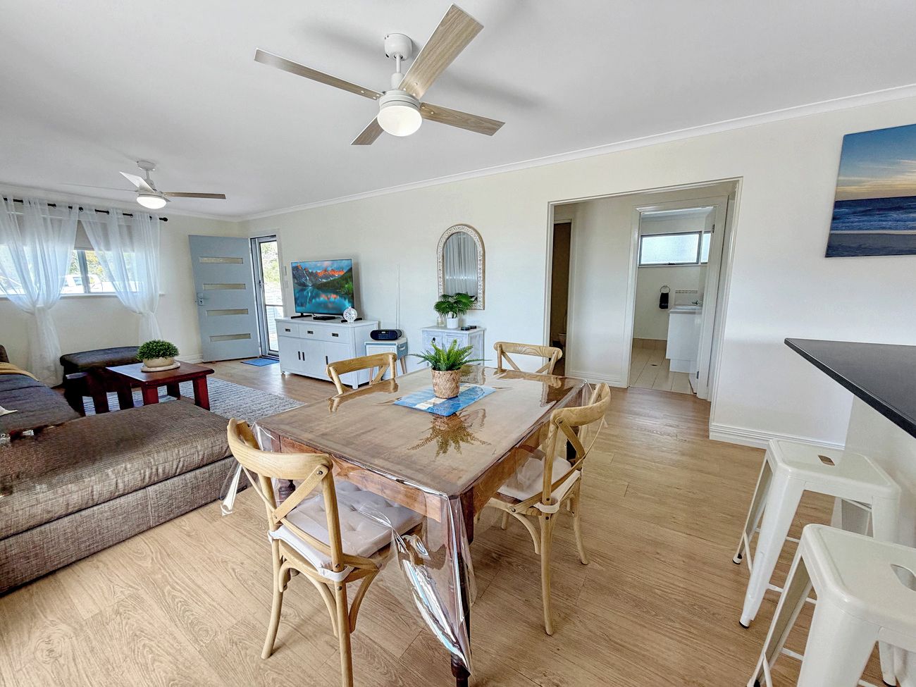 A spacious living area with a dining table, chairs, a sofa, and a ceiling fan.