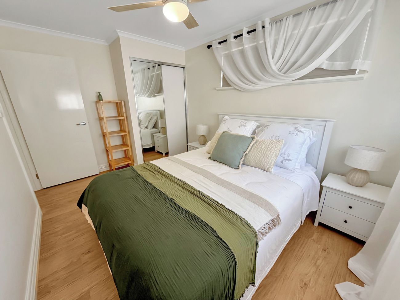 A bedroom with a bed, nightstand, lamp, and a ceiling fan.