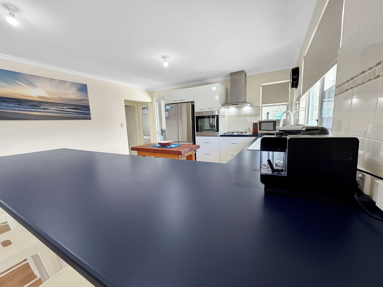 A modern kitchen with a dark countertop, white cabinets, and a built-in oven.