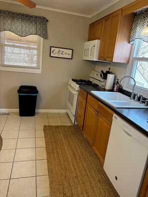 A kitchen with a stove, microwave, sink, and wooden cabinets. - Cute and Cozy 3 Bedroom House in Saint Albans (Saint Albans)