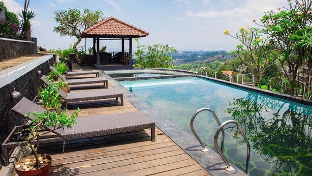 A pool area with lounge chairs, a gazebo, and a view of the landscape. - Dago Highland Resort (Bandung)