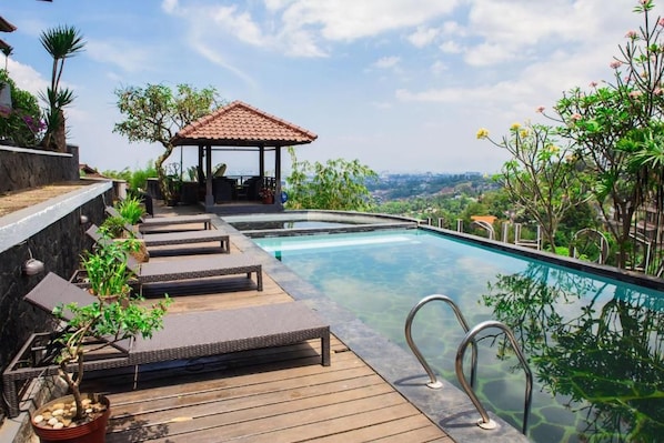 A pool area with lounge chairs, a gazebo, and a view of the landscape. - Dago Highland Resort (Bandung)