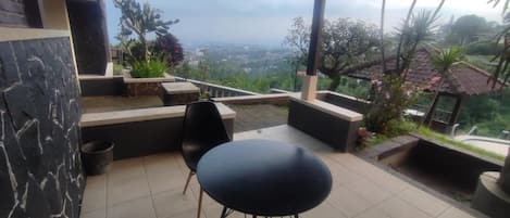 An outdoor patio with a black chair, a small table, and a view of a cityscape.