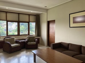 A room with a large window, a sofa, two armchairs, and a wooden coffee table. - Dago Highland Resort (Bandung)