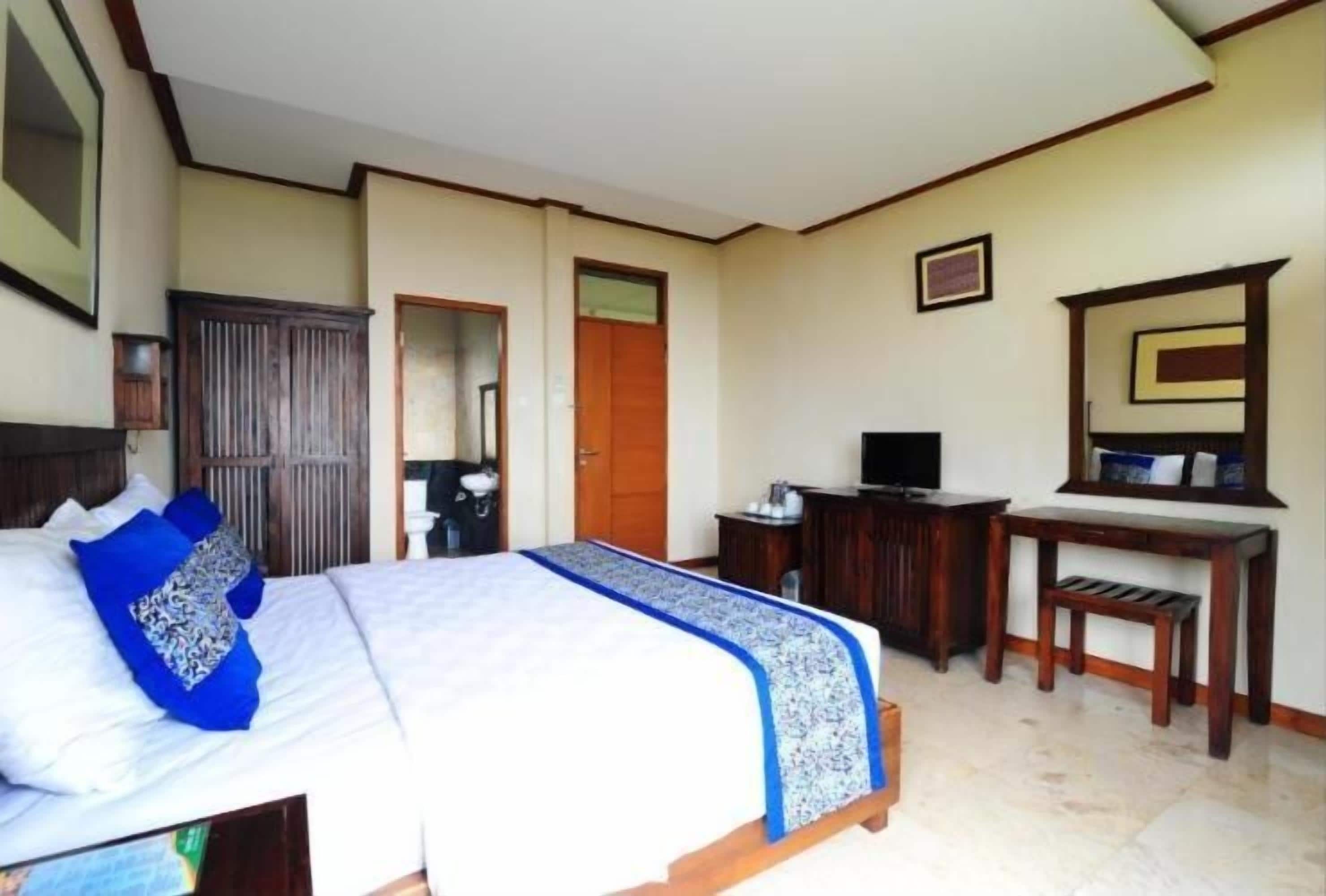 A bedroom with a bed, a desk, a television, and a wardrobe.