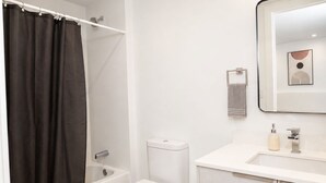 A bathroom with a bathtub, toilet, and a sink with a mirror above it. - Luxury 1.65M 4-Story Townhome 3bed/3bath in the Heart of Brickell (Miami)