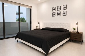 Une chambre moderne avec un grand lit, une porte-fenêtre coulissante donnant sur un balcon et une série d’œuvres d’art murales sur le thème de l’automobile.