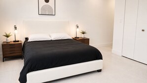 A modern bedroom with a large bed, two bedside tables with lamps, and a wall-mounted artwork. - Luxury 1.65M 4-Story Townhome 3bed/3bath in the Heart of Brickell (Miami)