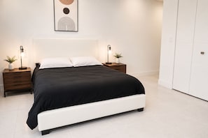 Une chambre moderne avec un grand lit, deux tables de chevet avec des lampes et une œuvre d’art accrochée au mur.
