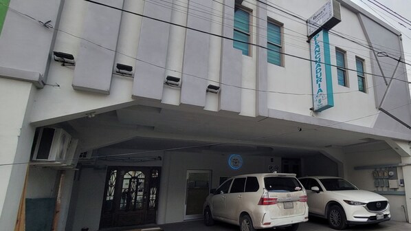 A building with a sign reading 'Chandigarh' and two parked cars.