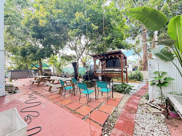 An outdoor patio with a barbecue area, picnic tables, and chairs.