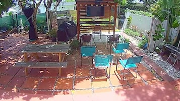 An outdoor patio with a wooden pergola, a barbecue grill, and several chairs and tables.