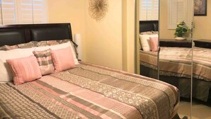 Quarto com cama, espelho e um ornamento na parede.