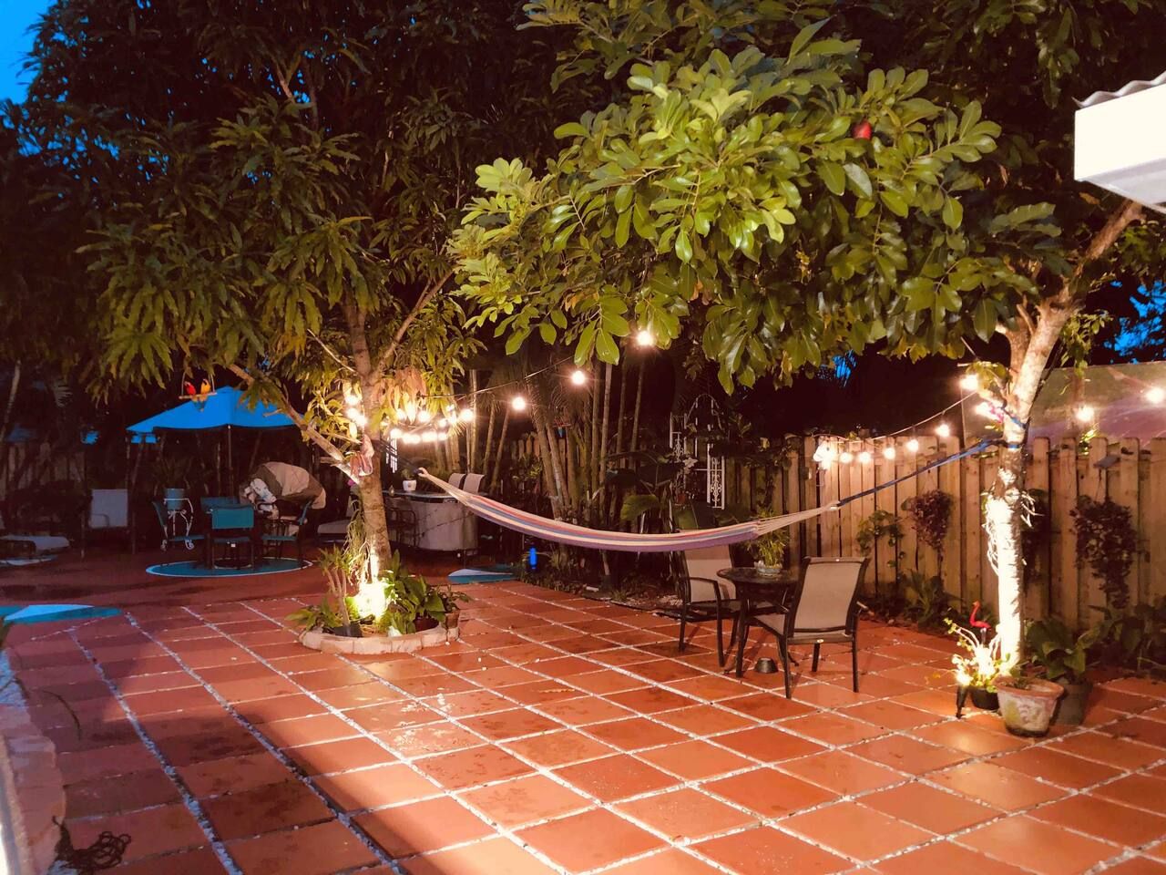 An outdoor patio with a hammock, seating area, and string lights.