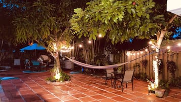 An outdoor patio with a hammock, seating area, and string lights.