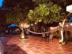 Un patio al aire libre con una hamaca, zona de estar e iluminación colgante.