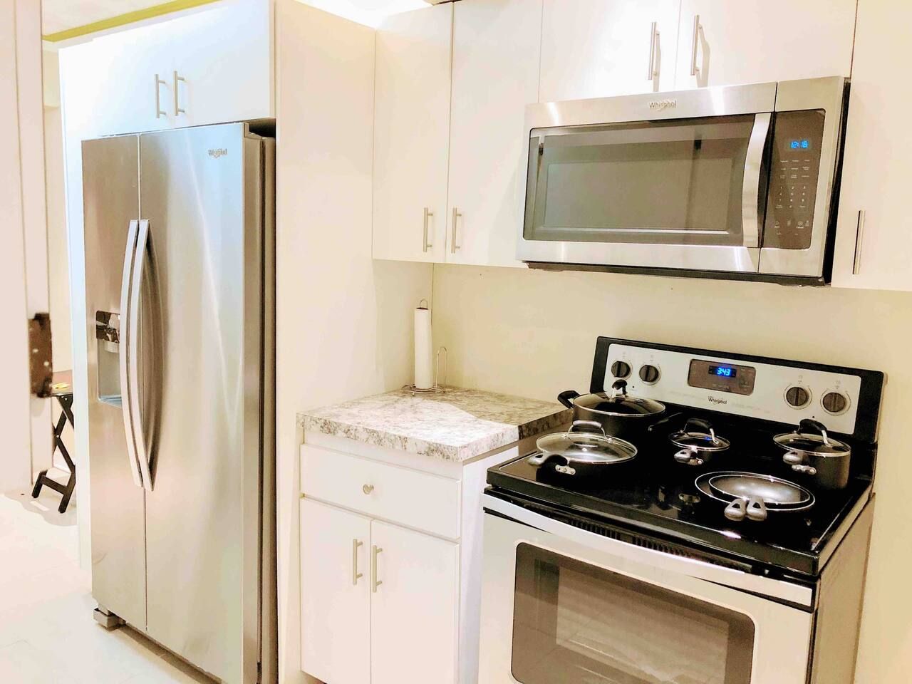 A kitchen with a stainless steel refrigerator, a microwave, and a stove with pots.