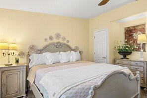 Een slaapkamer met een bed, nachtkastjes, een deur en een wanddecoratie.