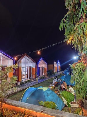 A campsite with tents and a building with a glass facade.