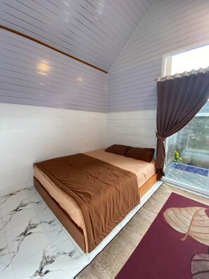 Une chambre à coucher avec un lit, une fenêtre avec des rideaux et une vue sur l’extérieur.