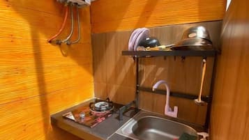 A compact kitchen with a gas stove, sink, and a gas cylinder.
