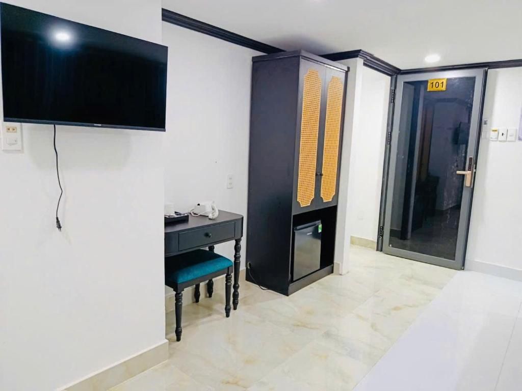 Een hotelkamer met een flatscreen televisie aan de muur, een bureau met stoel, een minibar en een deur met het nummer 101.