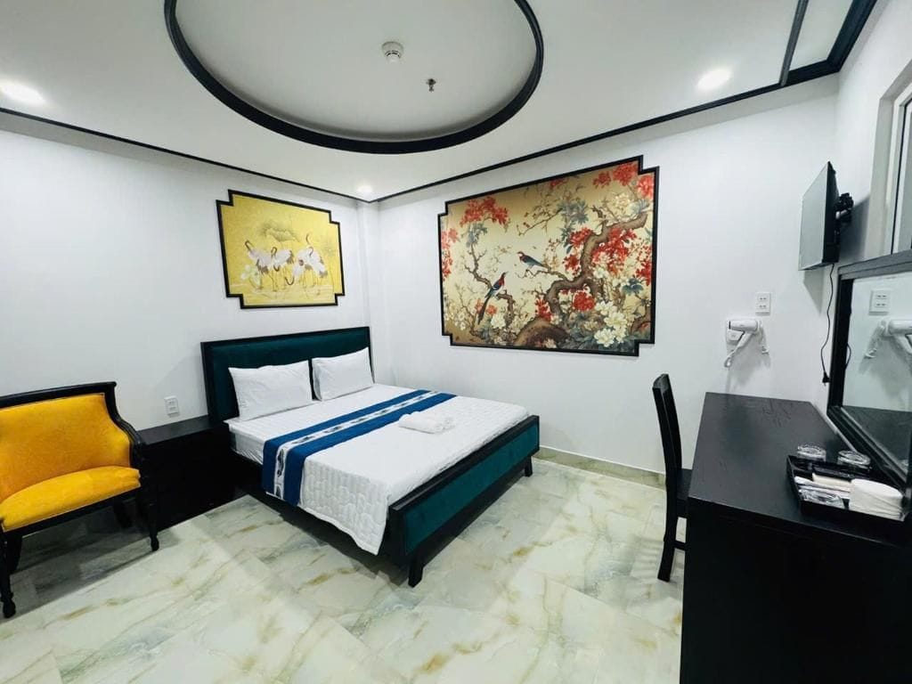 Een hotelkamer met een bed, een bureau, een stoel en kunstwerken aan de wanden.