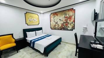 Een hotelkamer met een bed, een bureau, een stoel en kunstwerken aan de wanden.