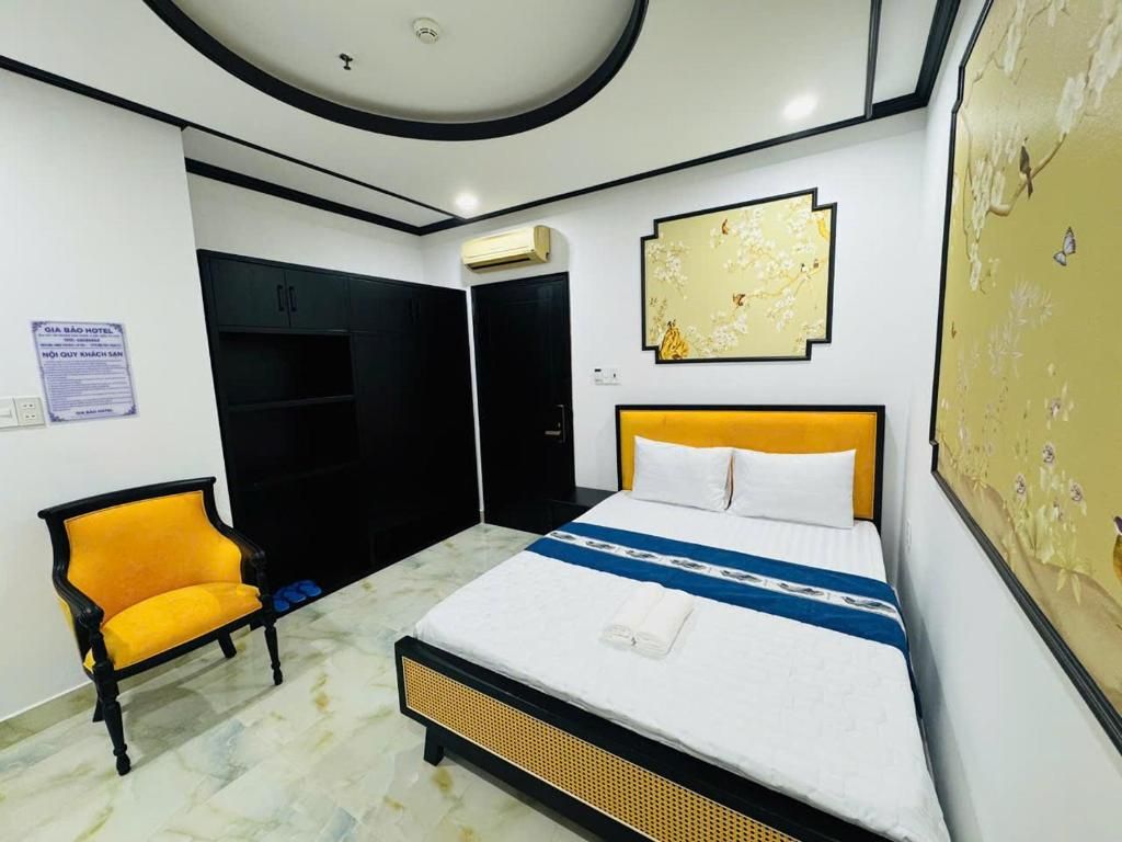 Une chambre d’hôtel avec un lit, une chaise, une armoire et un mur orné d’un motif floral.