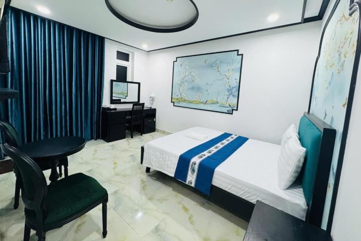 A hotel room with a bed, a desk, a chair, and a television.